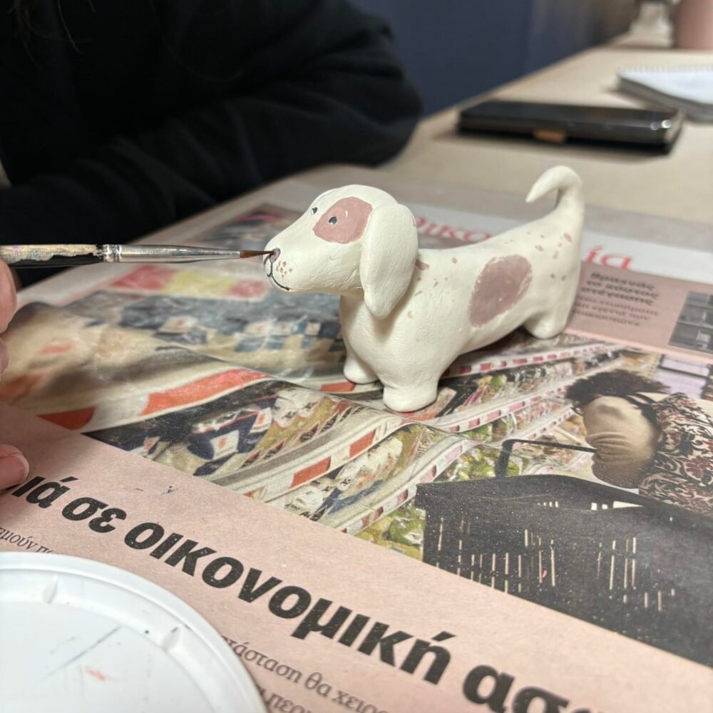 Διαδικασία ζωγραφικής σε πήλινο γλυπτό σκυλάκι, ένα από τα βασικά στάδια που μαθαίνετε στα μαθήματα κεραμικής στο εργαστήριό μας Theta for Ceramics στου Ζωγράφου.